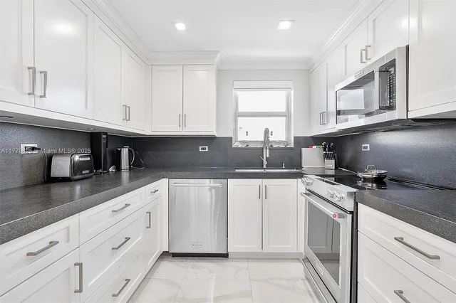 a kitchen with cabinets appliances a sink and a counter top space