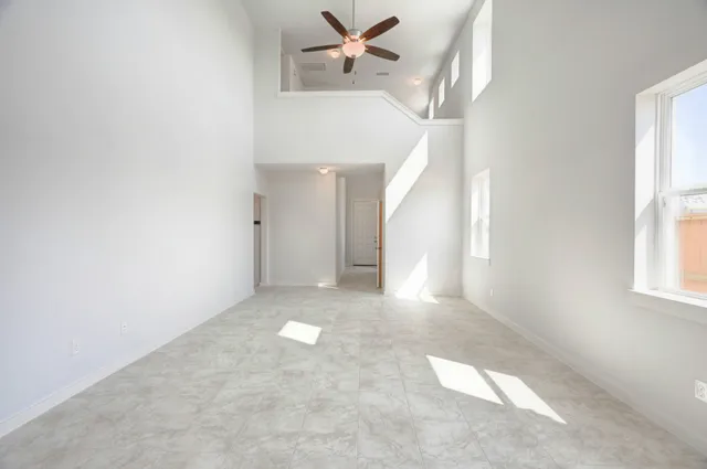 an empty room with windows and fan