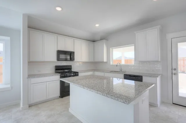 a kitchen with stainless steel appliances granite countertop a sink a stove a microwave a refrigerator a sink and white cabinets