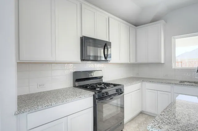 a kitchen with granite countertop white cabinets and stainless steel appliances