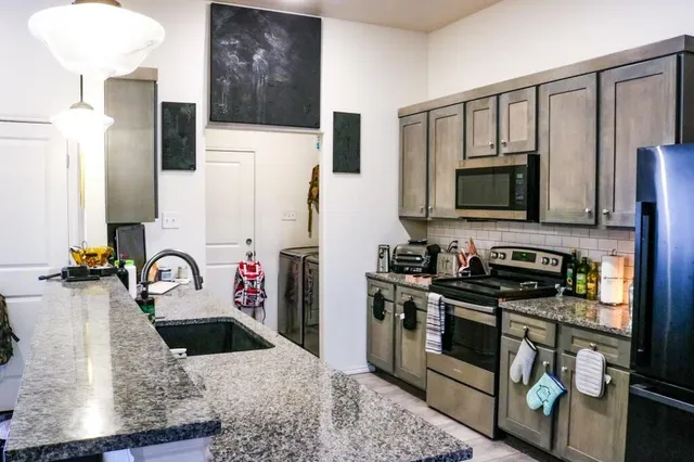 a kitchen with stainless steel appliances granite countertop a sink stove and refrigerator