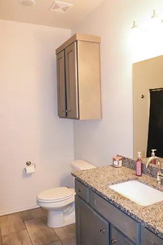 a bathroom with a granite countertop toilet sink and mirror