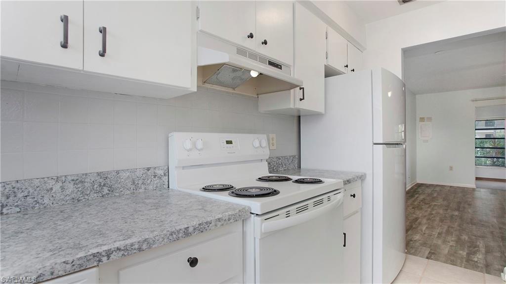 600 Valley Stream Drive, Unit I Naples, FL 34113 - Photo 14 of 20 Kitchen with white range with electric cooktop, light countertops, under cabinet range hood, and white cabinetry