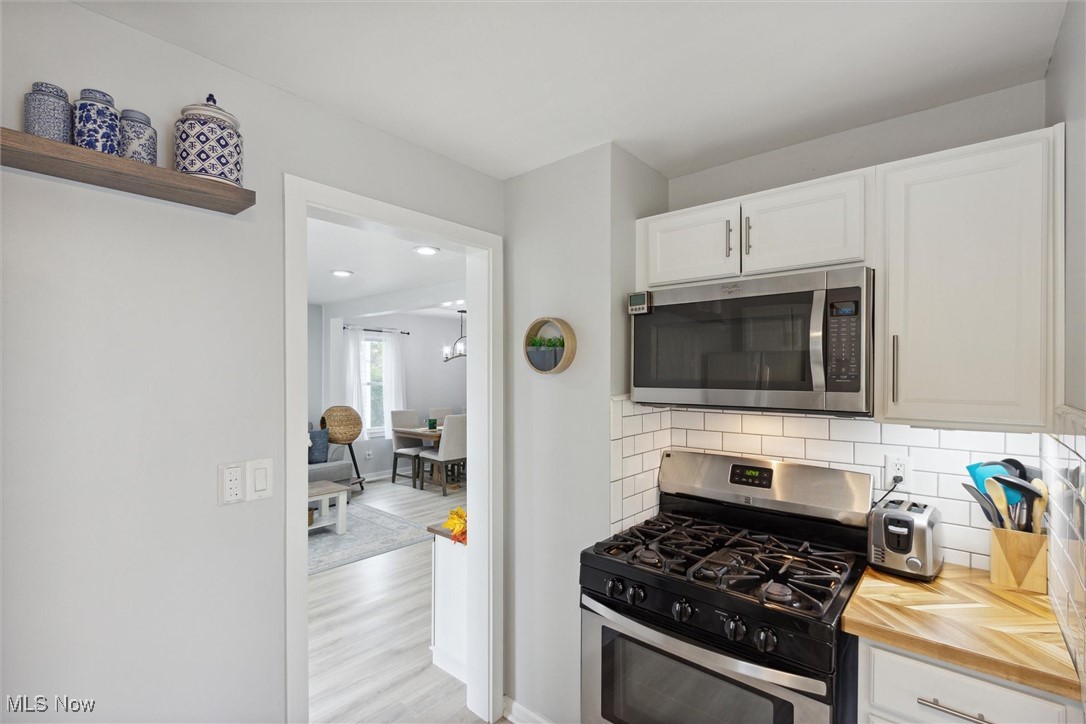 373 Erie Road Vermilion, OH 44089 - Photo 13 of 29 Kitchen with light hardwood / wood-style floors, white cabinets, stainless steel appliances, backsplash, and wooden counters
