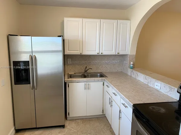a kitchen with a refrigerator sink and cabinets