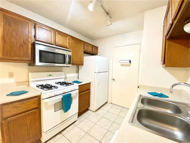 a kitchen with granite countertop a sink stove and refrigerator