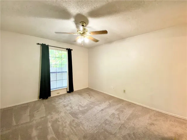 an empty room with chandelier fan and windows