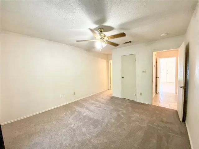 an empty room with closet and a ceiling fan