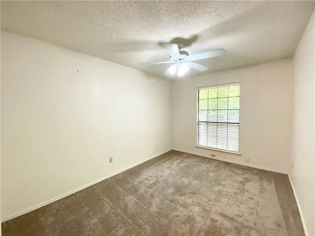 an empty room with chandelier fan and windows