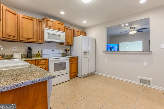 a kitchen with stainless steel appliances granite countertop a stove a sink dishwasher and a refrigerator with wooden floor
