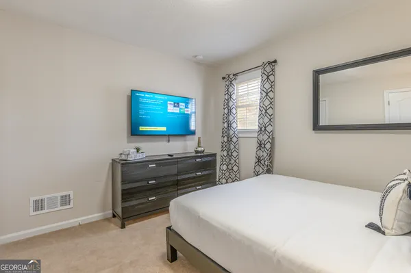 a bedroom with a bed and a flat tv screen on dresser