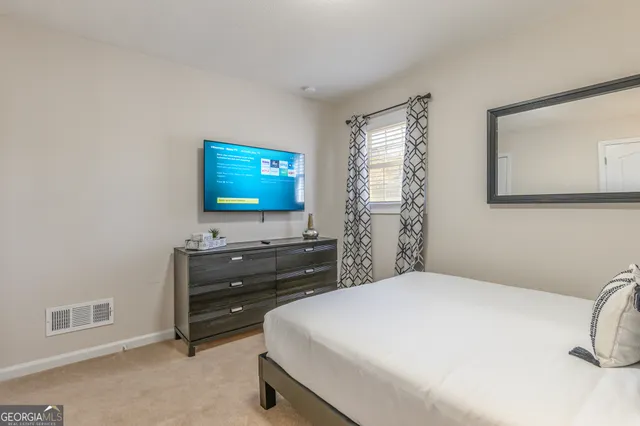 a bedroom with a bed and a flat tv screen on dresser