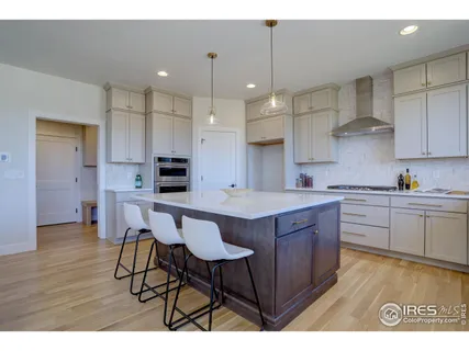 a open kitchen with stainless steel appliances granite countertop a sink dishwasher a stove a refrigerator and white cabinets with wooden floor