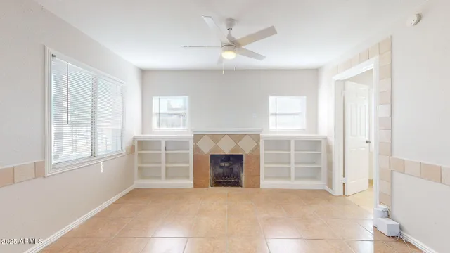 an empty room with windows and fireplace