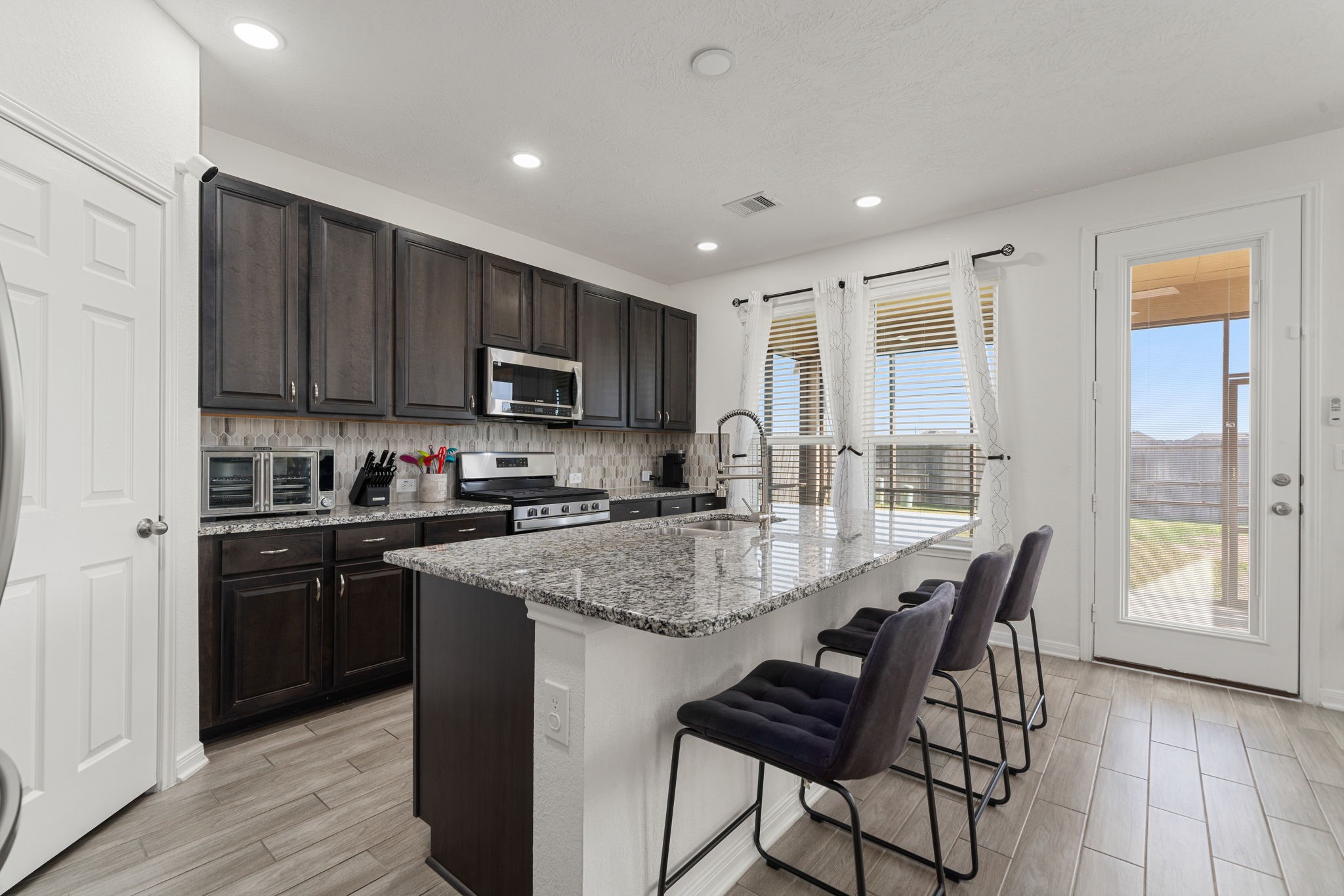 20811 Filbert Lane Katy, TX 77449 - Photo 10 of 43 a kitchen with stainless steel appliances granite countertop a stove a sink dishwasher a microwave oven and a refrigerator with wooden floor