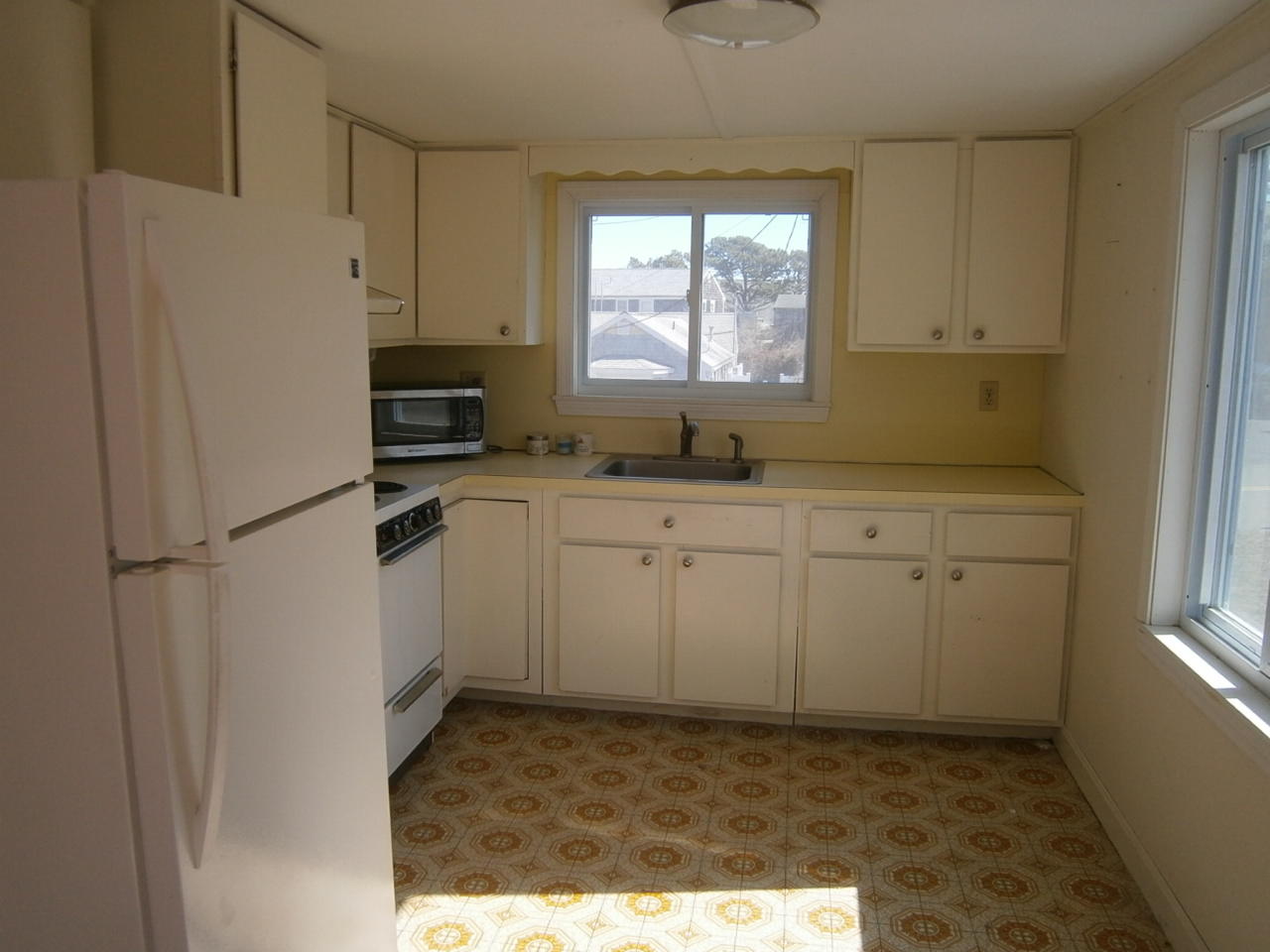 207 Captain Chase Road Dennis Port, MA 02639 - Photo 11 of 12 a kitchen with white cabinets sink and white appliances