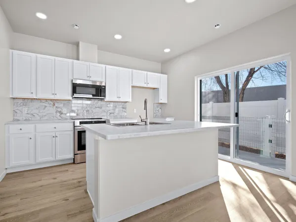 a kitchen with kitchen island granite countertop a sink cabinets and stainless steel appliances