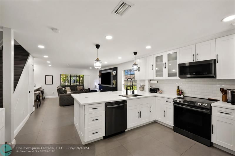a kitchen with stainless steel appliances a sink a stove a microwave a center island and cabinets