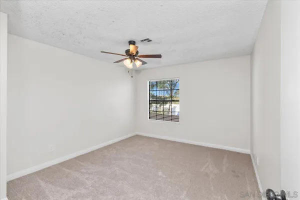 an empty room with windows and fan
