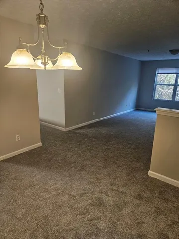 an empty room with a chandelier fan and windows