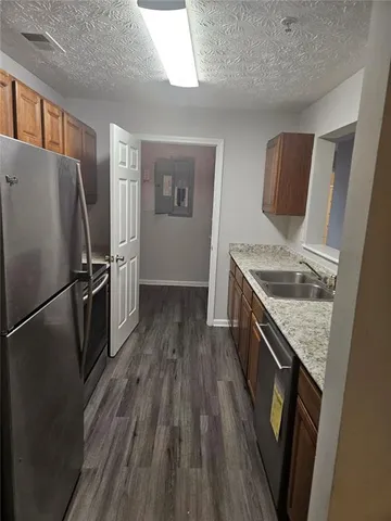 a kitchen with granite countertop a refrigerator stove and wooden floor