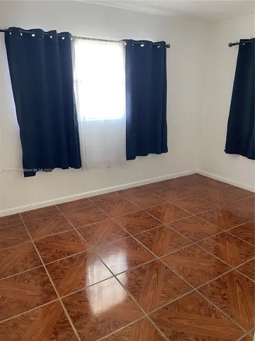 a view of an empty room with wooden floor and a cabinet
