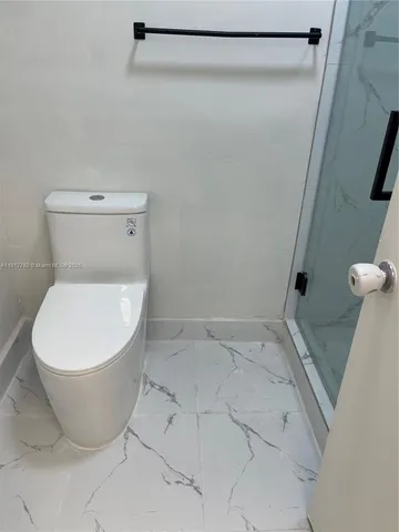 a white toilet sitting next to a shower