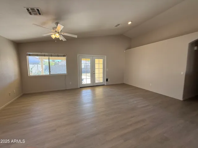 an empty room with windows and ceiling fan