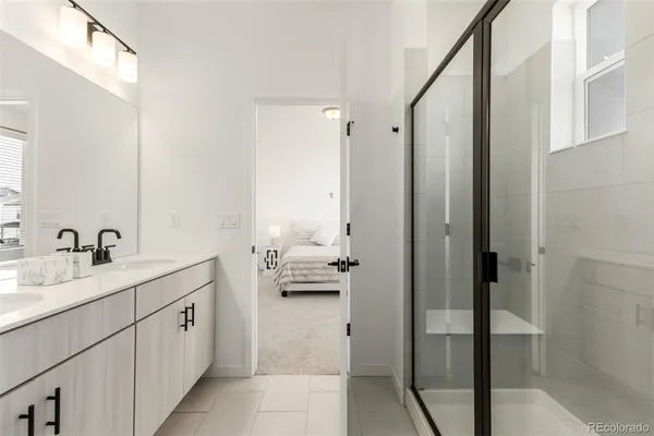 a en suite bathroom with a double vanity sink a mirror and shower