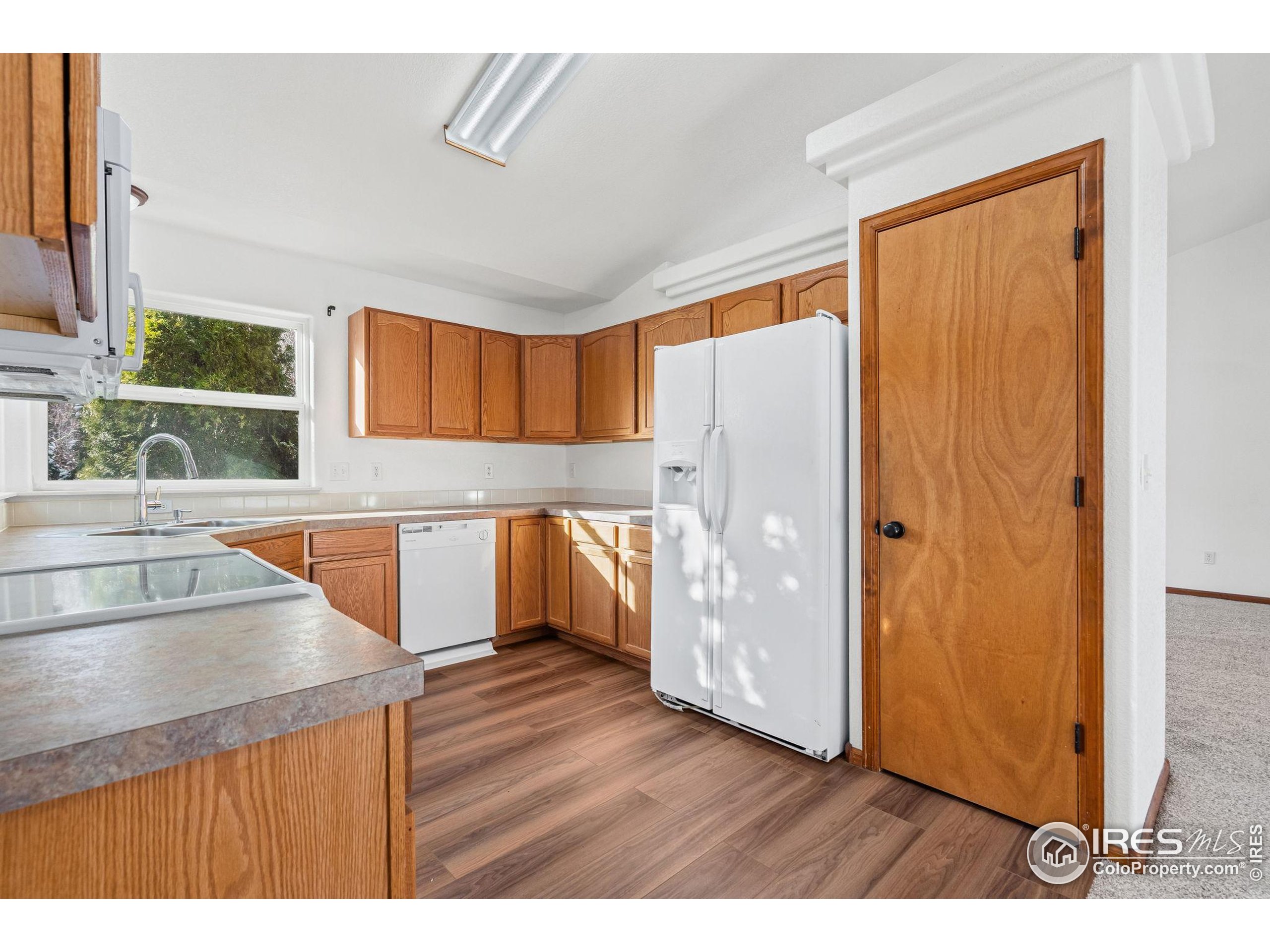 2239 Muir Lane Fort Collins, CO 80524 - Photo 11 of 31 a kitchen with kitchen island granite countertop wooden floors a refrigerator and a sink