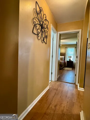a view of a hallway with wooden floor and a bathroom