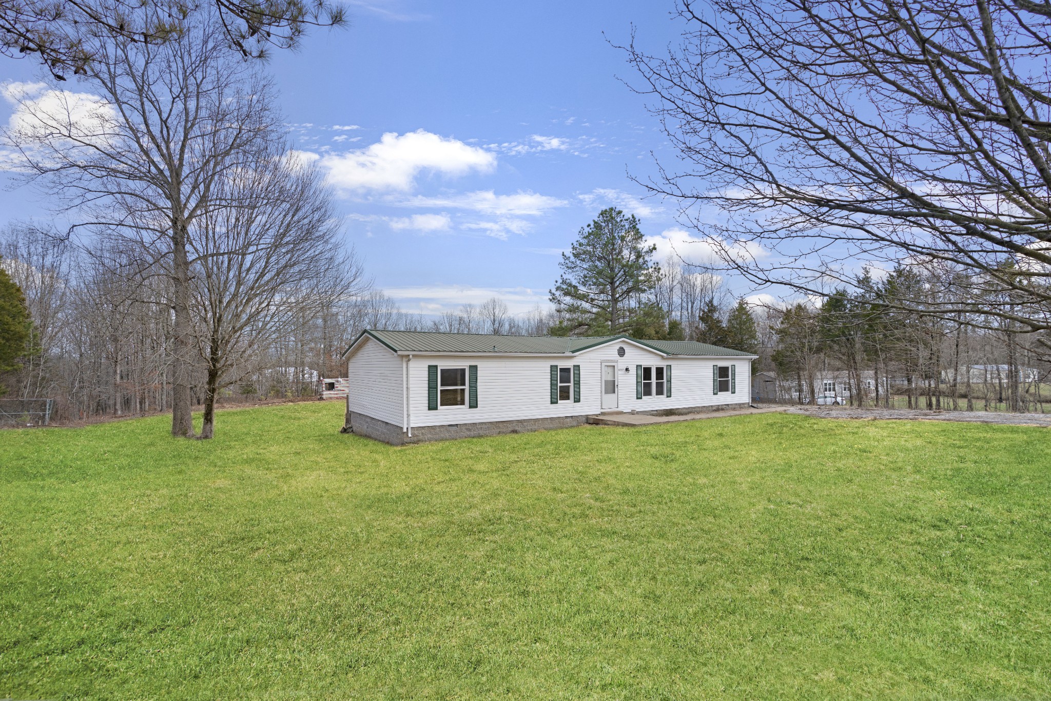 4227 Old Metal Road Palmyra, TN 37142 - Photo 1 of 16 a house that is sitting in the grass with large trees and plants