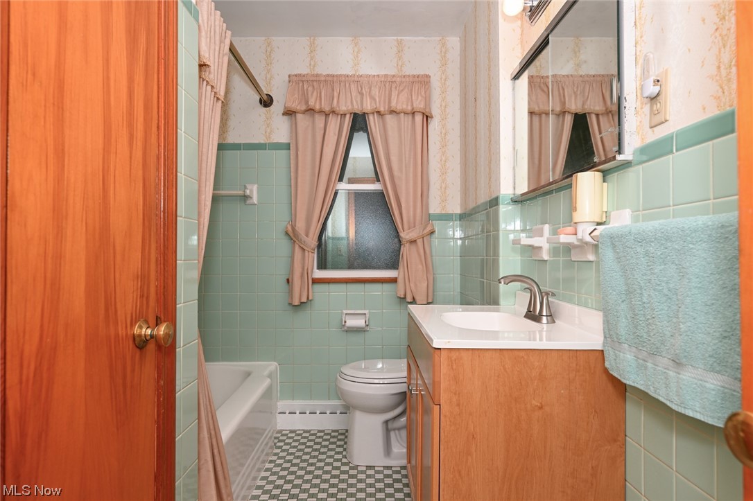849 Bears Den Road Youngstown, OH 44511 - Photo 12 of 28 Full bathroom with tiled shower / bath combo, vanity, mirror, tile walls, a baseboard heating unit, backsplash, and light tile floors