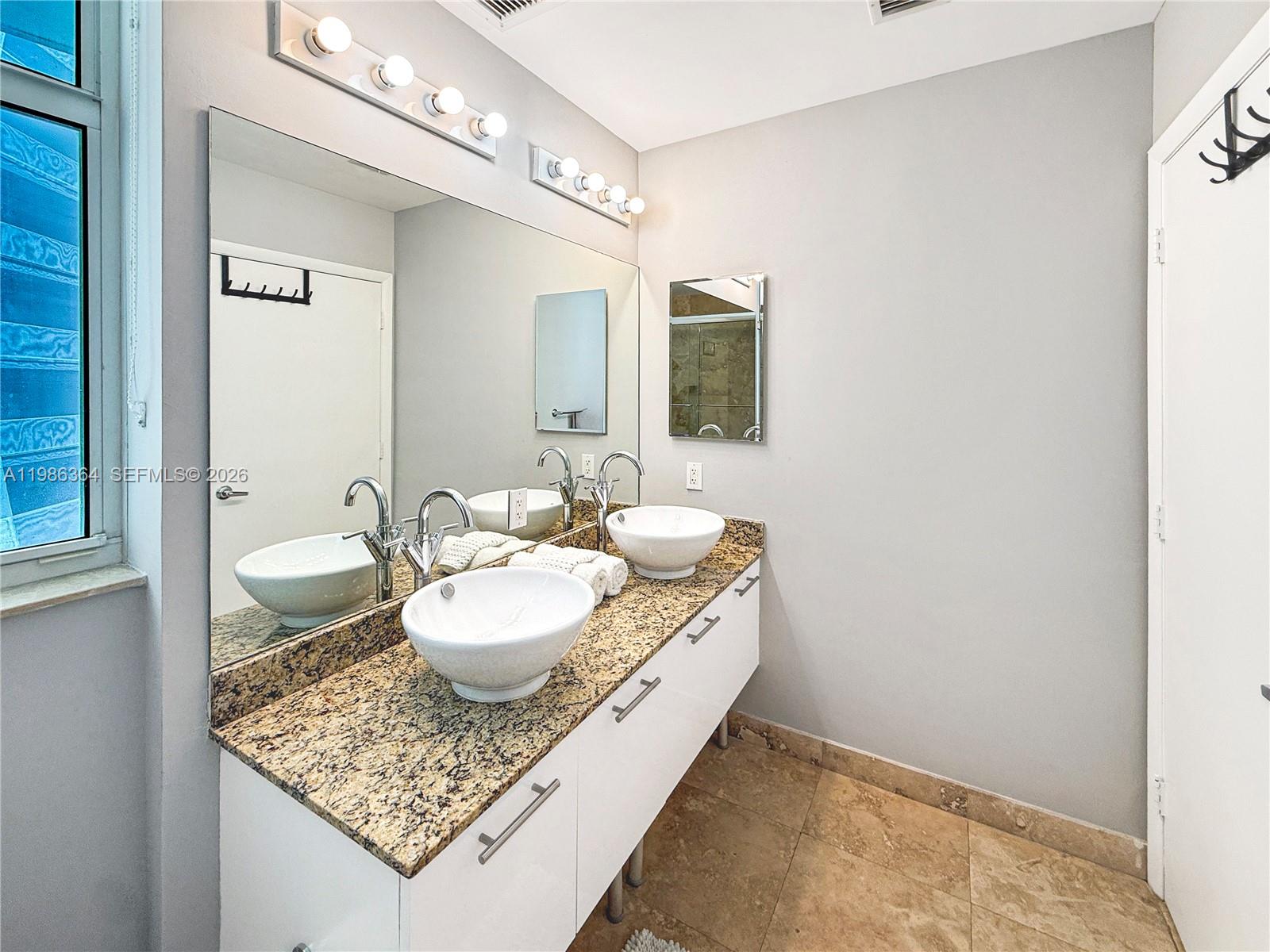 41 Southeast 5th Street, Unit 602 Miami, FL 33131 - Photo 13 of 43 a bathroom with a granite countertop sink a toilet and a mirror
