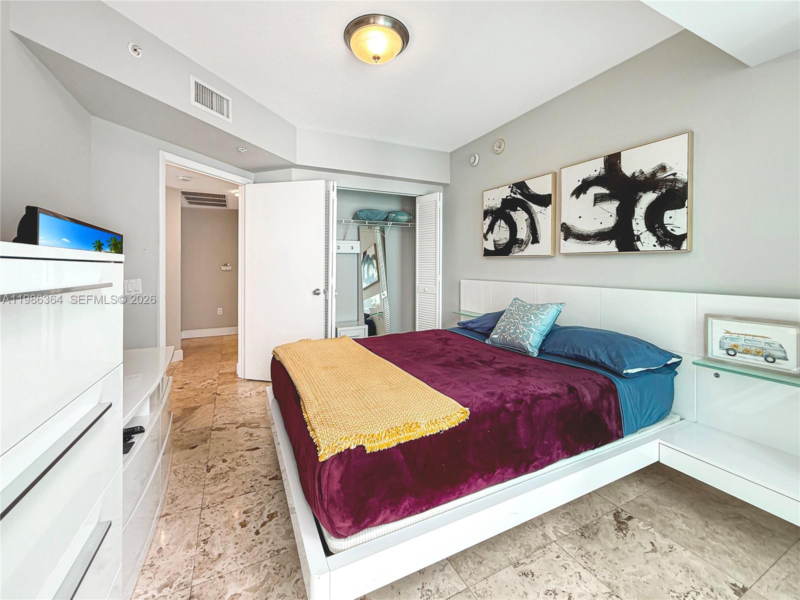 41 Southeast 5th Street, Unit 602 Miami, FL 33131 - Photo 15 of 43 a bedroom with a bed and a refrigerator