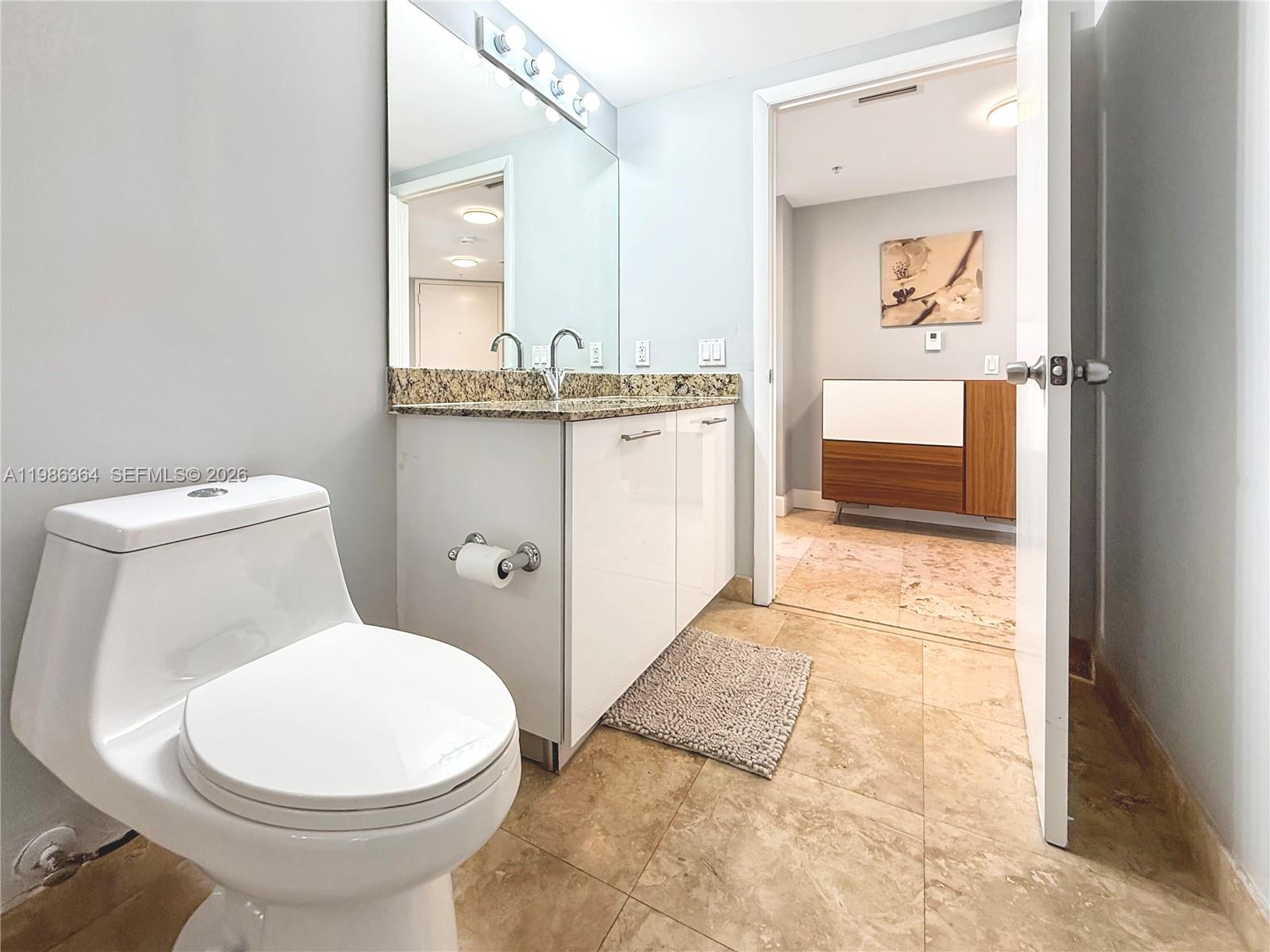 41 Southeast 5th Street, Unit 602 Miami, FL 33131 - Photo 17 of 43 a bathroom with a toilet a sink and mirror