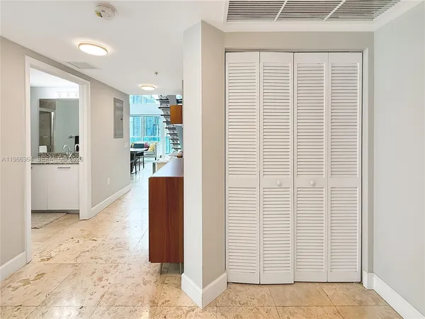 a view of a hallway with wooden cabinets and dining room