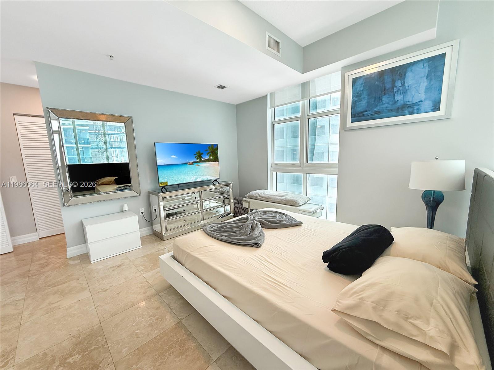 41 Southeast 5th Street, Unit 602 Miami, FL 33131 - Photo 9 of 43 a bedroom with a bed and a flat screen tv