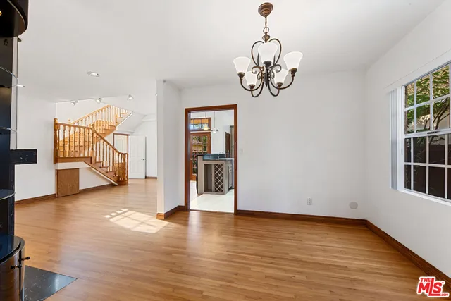 a view of an empty room with wooden floor and windows