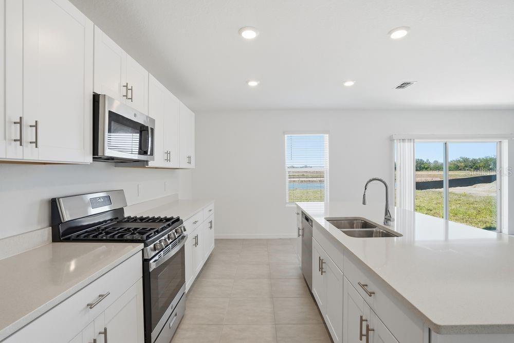 13243 Commons Avenue Parrish, FL 34219 - Photo 5 of 44 a kitchen with stainless steel appliances a sink stove and cabinets