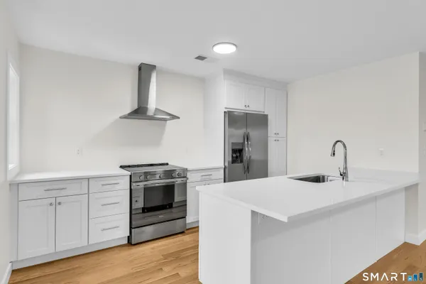 a kitchen with stainless steel appliances a sink dishwasher and a stove top oven with wooden floor