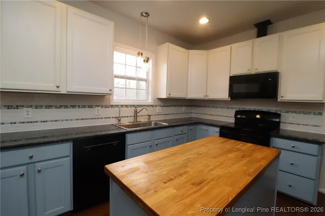 a kitchen with a sink and a stove with wooden floor
