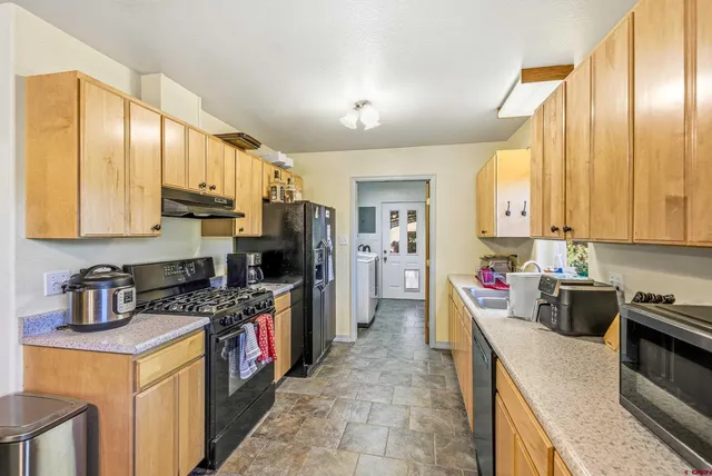 a kitchen with stainless steel appliances granite countertop a stove sink refrigerator and cabinets