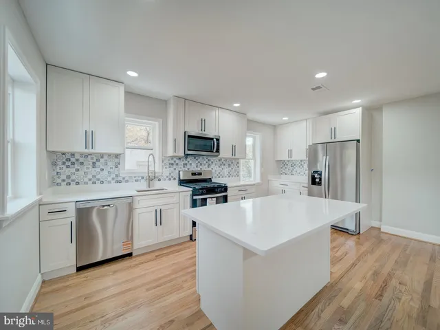 a large kitchen with a center island wooden floor stainless steel appliances and cabinets