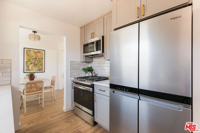 a kitchen with stainless steel appliances a refrigerator a stove and white cabinets