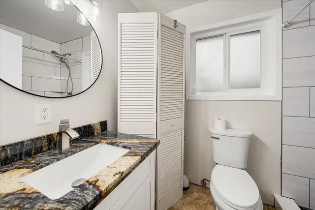 a bathroom with a granite countertop sink a toilet and mirror