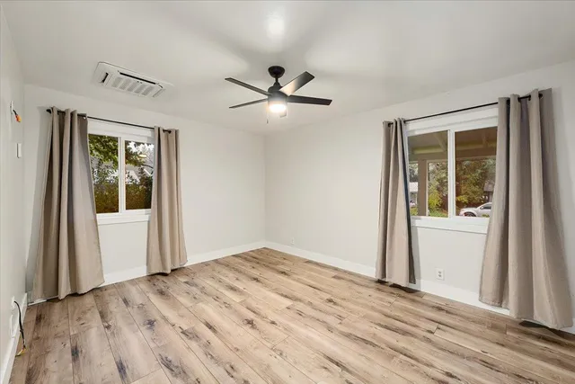 a view of empty room with wooden floor and fan