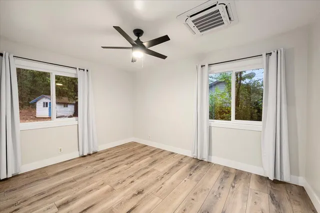 a view of empty room with wooden floor and fan