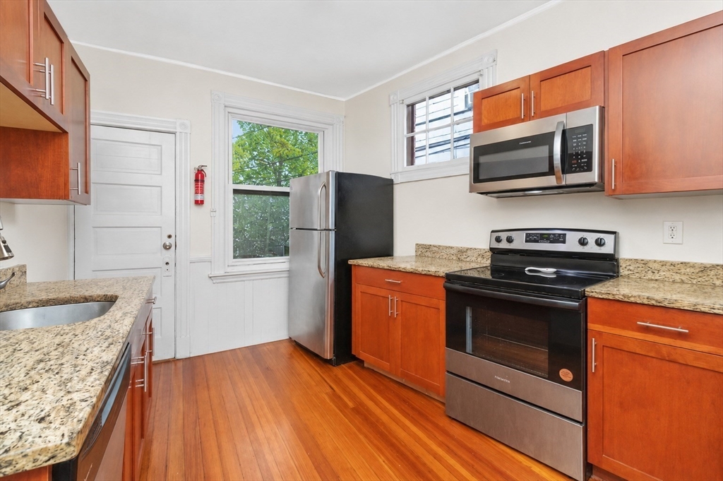 8 Colliston Road Boston, MA 02135 - Photo 14 of 40 a kitchen with stainless steel appliances granite countertop a stove microwave and refrigerator
