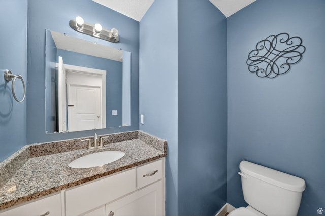 295 Spruce Way Santaquin, UT 84655 - Photo 12 of 32 Bathroom featuring a white vanity with brushed nickel hardware, a speckled stone countertop, and an undermount sink